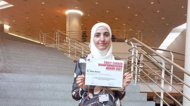 Image of Heba holding their Early Bioinformatician Award